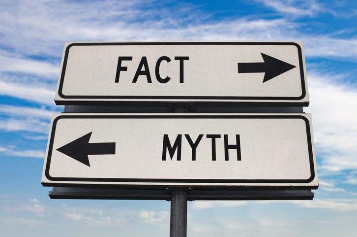 A street sign pointing in opposing directions, reading “fact” and “myth.” 